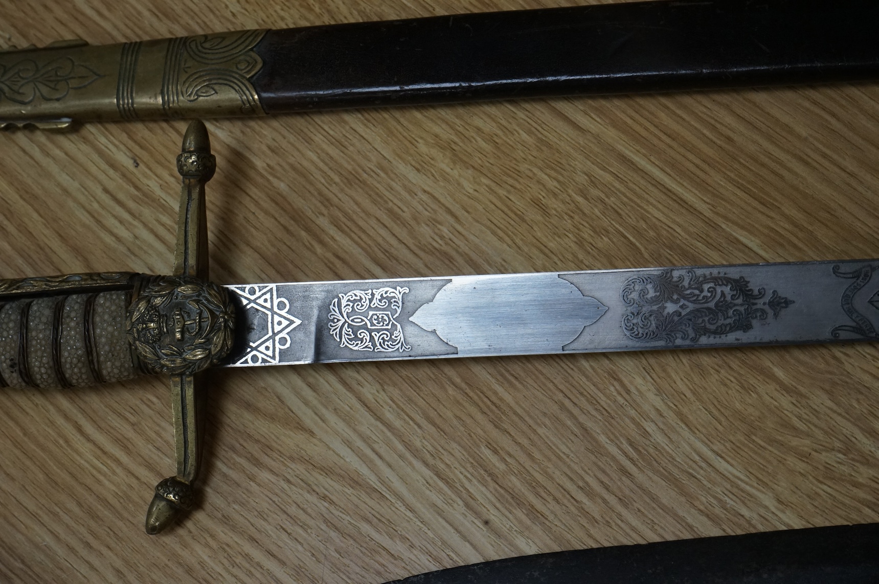 A post 1902 Naval Officer’s Dirk, the regulation blade with crowned fouled anchor, regulation hilt with remains of bullion dress knot in its leather scabbard with brass mounts, locket engraved with owners initials; RSA